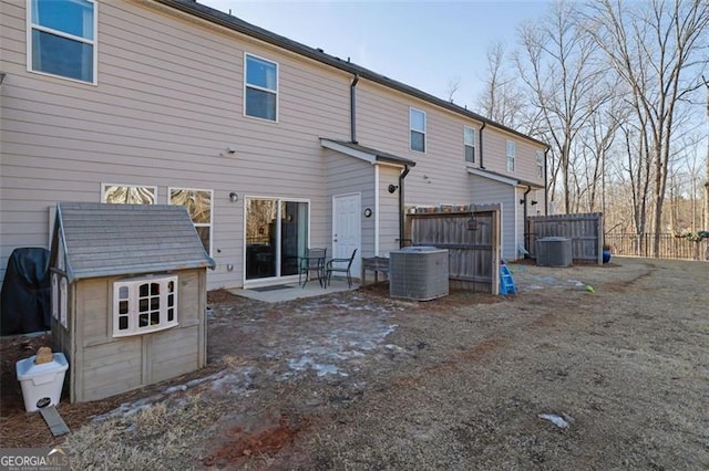 back of house with central AC unit and a storage unit