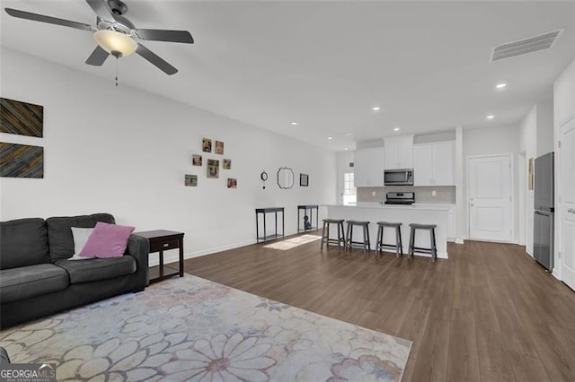 living room featuring ceiling fan and dark hardwood / wood-style flooring