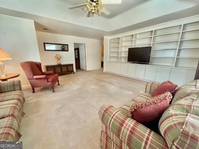 carpeted living room featuring ceiling fan and built in features