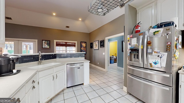 kitchen featuring light tile patterned floors, white cabinetry, stainless steel appliances, lofted ceiling, and sink