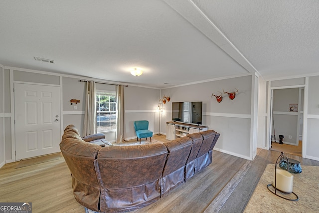 living room featuring crown molding, a textured ceiling, and light hardwood / wood-style flooring