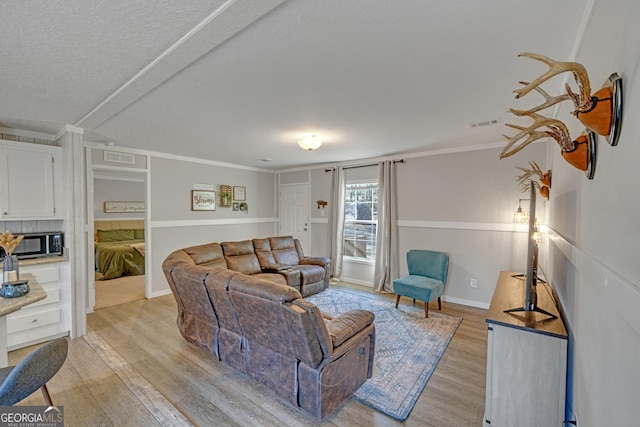 living room with light wood-type flooring and crown molding