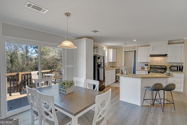 dining room with light wood-type flooring and a textured ceiling