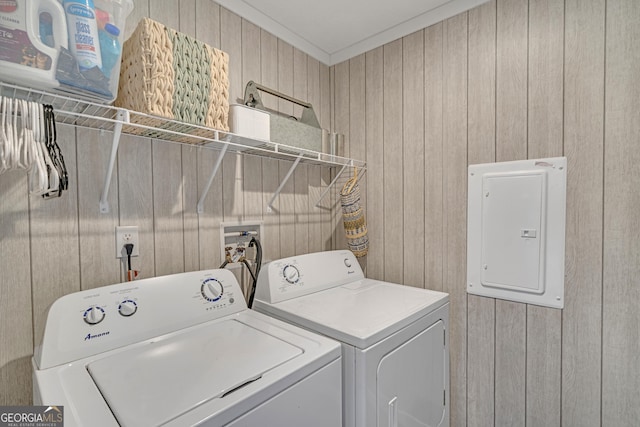 clothes washing area with crown molding, washer and dryer, wooden walls, and electric panel