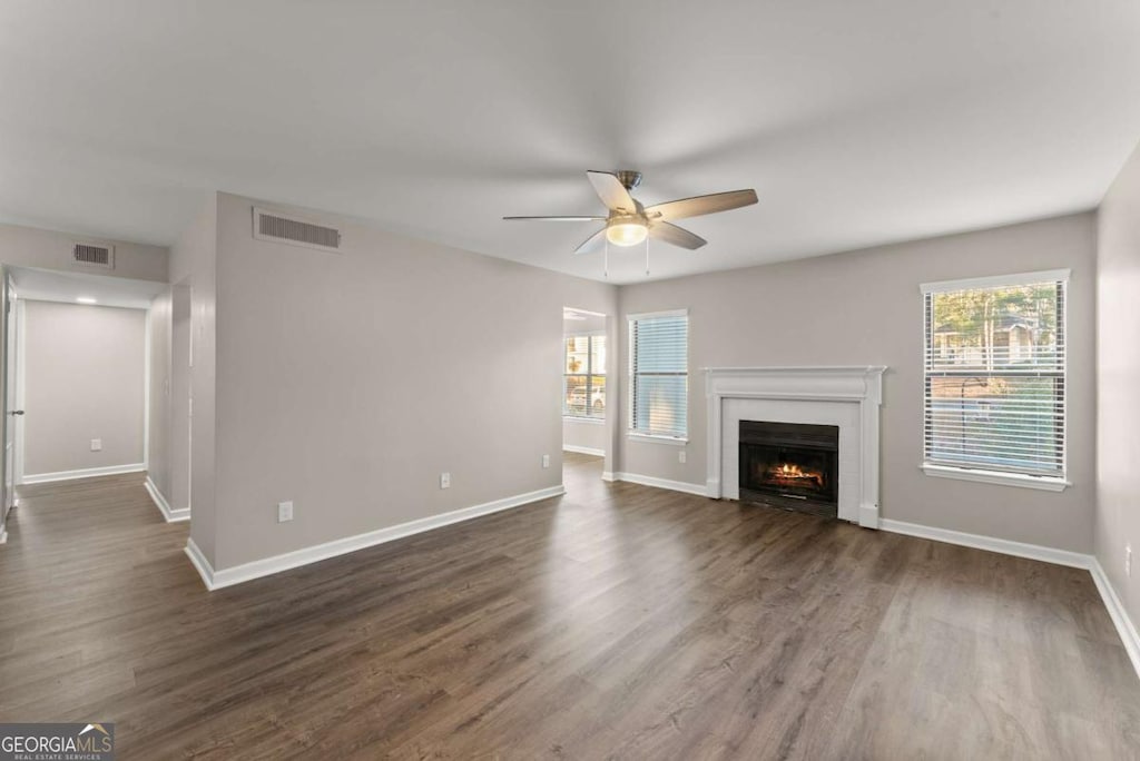 unfurnished living room with ceiling fan, dark hardwood / wood-style flooring, and a healthy amount of sunlight