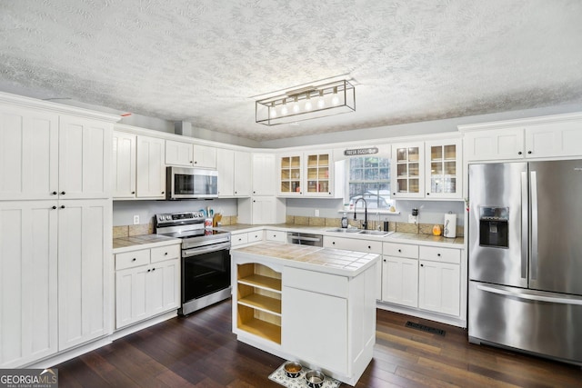 kitchen featuring sink, white cabinets, stainless steel appliances, and a kitchen island