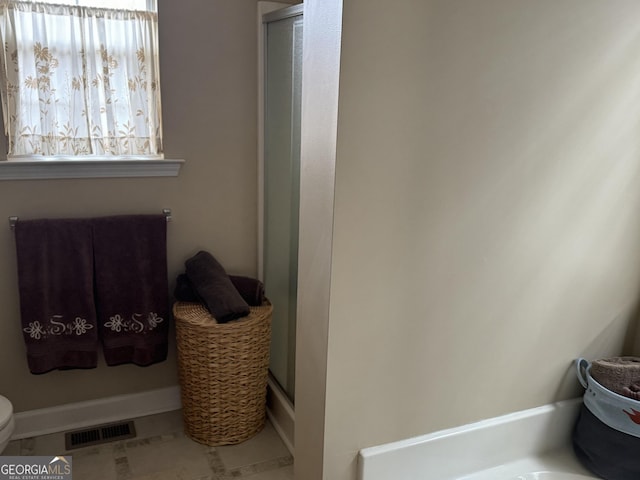 bathroom with tile patterned floors, an enclosed shower, and toilet