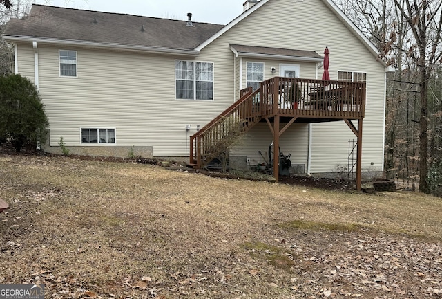 rear view of property with a wooden deck and a lawn