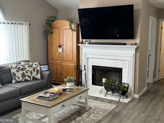 living room with vaulted ceiling, a high end fireplace, and hardwood / wood-style flooring