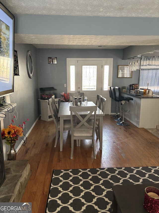 dining room featuring a textured ceiling and dark hardwood / wood-style flooring