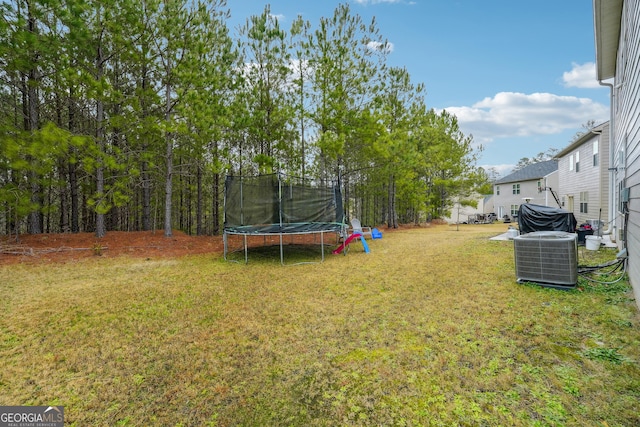 view of yard with central AC unit and a trampoline