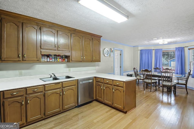 kitchen featuring a peninsula, a sink, light countertops, dishwasher, and light wood finished floors