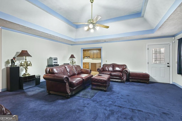 living room featuring ceiling fan, a tray ceiling, and carpet flooring