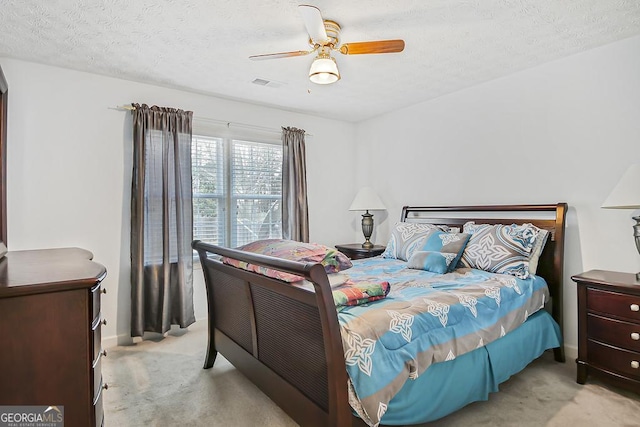 carpeted bedroom featuring a ceiling fan, visible vents, and a textured ceiling