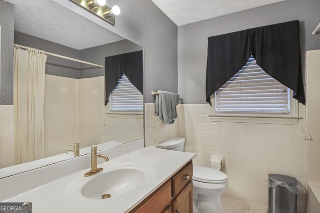 full bath featuring a wainscoted wall, toilet, vanity, a textured ceiling, and wallpapered walls