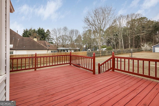 deck with a fenced backyard, a lawn, and an outdoor structure