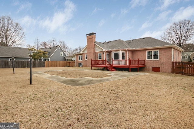 rear view of property featuring brick siding, a chimney, a shingled roof, a deck, and a fenced backyard