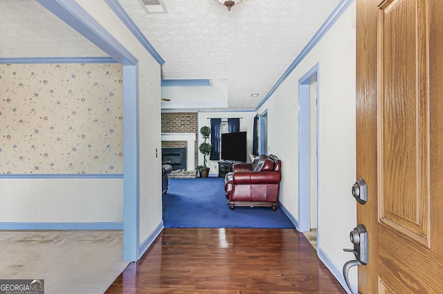 hallway featuring a textured ceiling, ornamental molding, wainscoting, and wallpapered walls