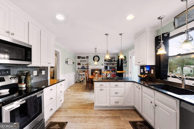 kitchen featuring sink, white cabinetry, hanging light fixtures, stainless steel appliances, and kitchen peninsula