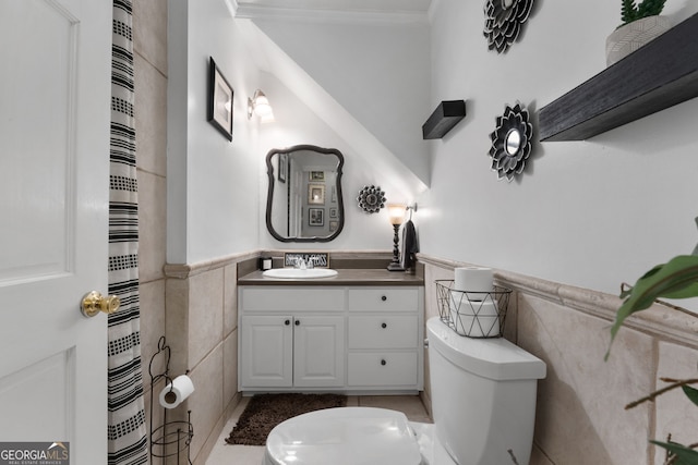 full bathroom with toilet, a wainscoted wall, and tile walls