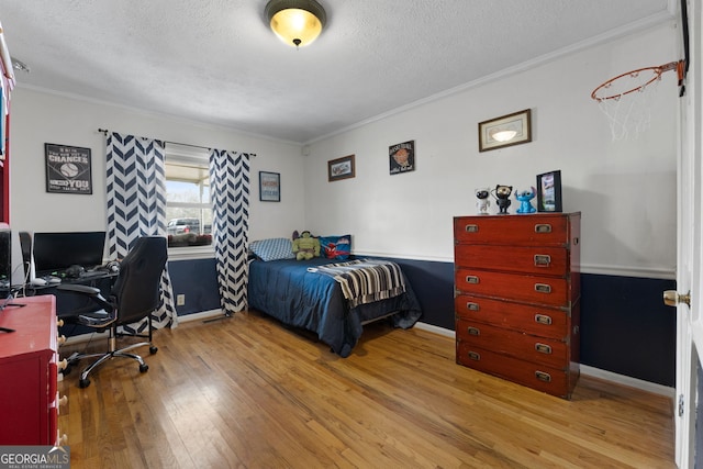 bedroom with crown molding, a textured ceiling, baseboards, and hardwood / wood-style floors