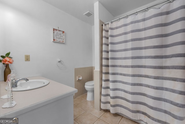 full bathroom featuring tile walls, visible vents, toilet, vanity, and tile patterned flooring