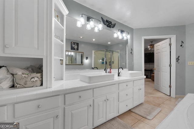 full bathroom with double vanity, a stall shower, a sink, and tile patterned floors