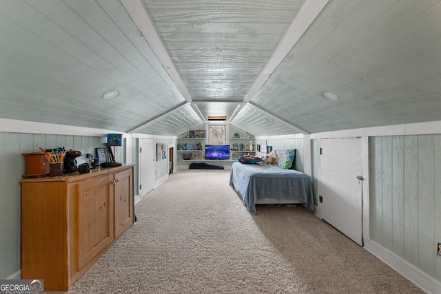 carpeted bedroom featuring wooden walls and vaulted ceiling