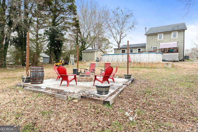 view of yard featuring an outdoor fire pit, an outdoor pool, an outdoor structure, a patio area, and a shed