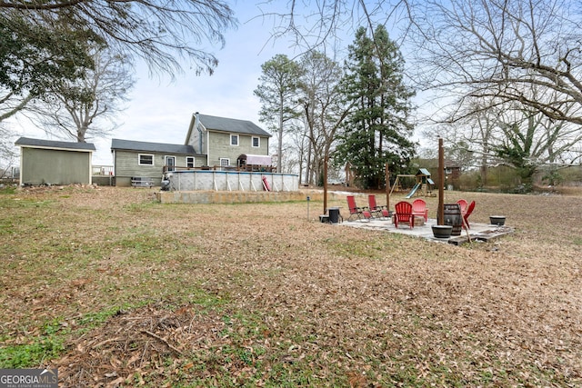 view of yard featuring a patio, an outdoor pool, a playground, and an outbuilding