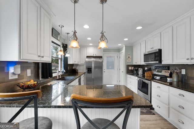 kitchen with pendant lighting, appliances with stainless steel finishes, a breakfast bar, and white cabinets