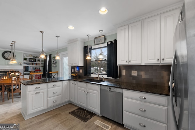 kitchen with a peninsula, white cabinets, stainless steel appliances, and a sink