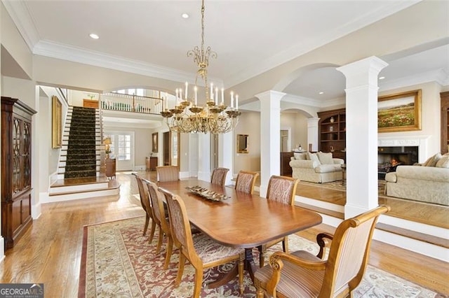 dining space with light hardwood / wood-style floors, ornamental molding, and an inviting chandelier