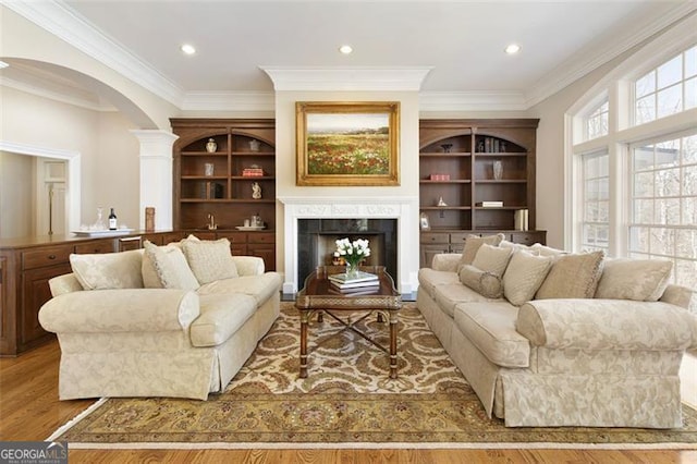 living room with crown molding, light hardwood / wood-style flooring, and built in shelves