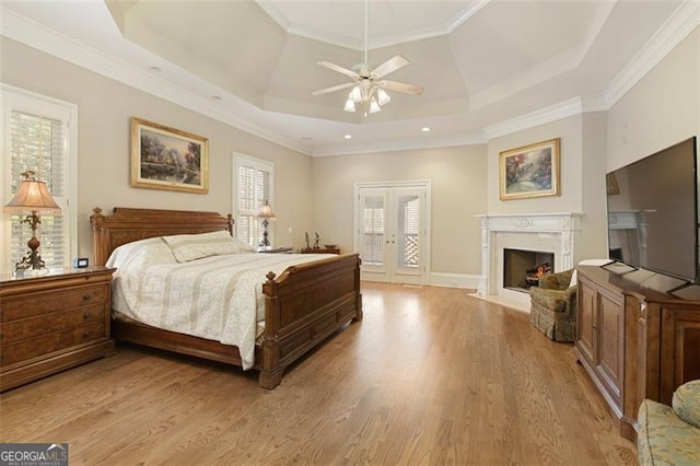 bedroom featuring light hardwood / wood-style floors, ceiling fan, access to outside, a tray ceiling, and crown molding