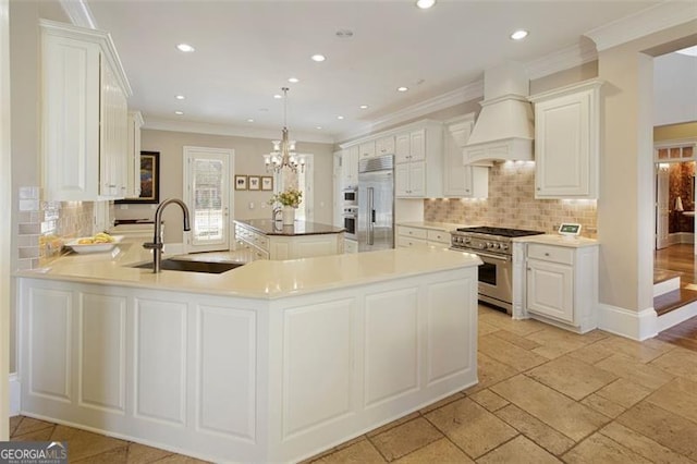 kitchen featuring premium range hood, kitchen peninsula, sink, hanging light fixtures, and premium appliances