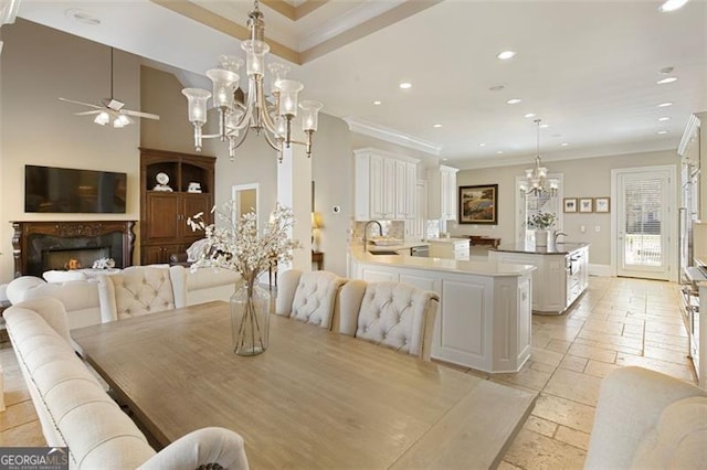 dining area featuring ceiling fan, a fireplace, sink, and ornamental molding