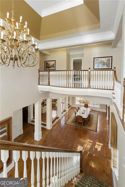 stairs with wood-type flooring, crown molding, and a chandelier