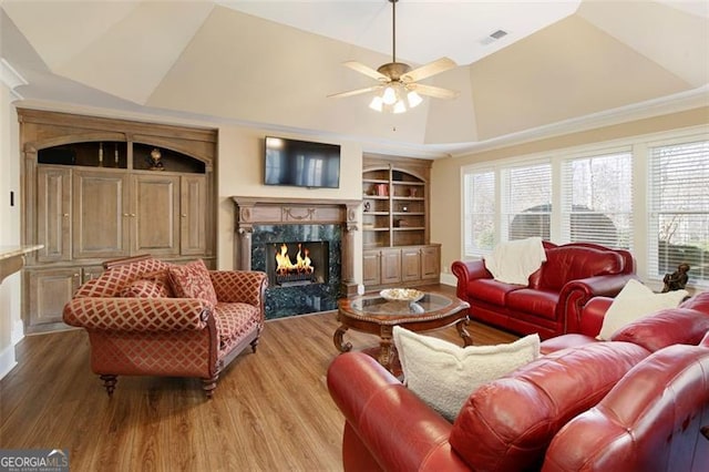 living room featuring a healthy amount of sunlight, vaulted ceiling, built in features, and a premium fireplace