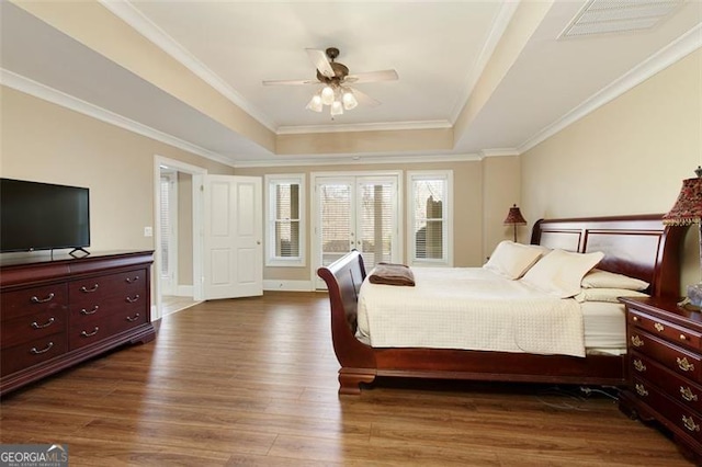 bedroom featuring ceiling fan, dark hardwood / wood-style floors, crown molding, and a raised ceiling