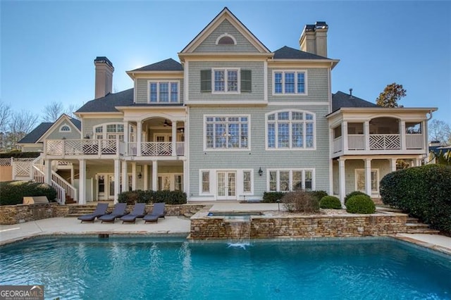 rear view of house featuring a swimming pool with hot tub and a patio