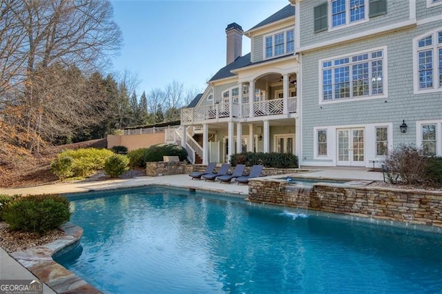 back of property with pool water feature, a patio area, and french doors