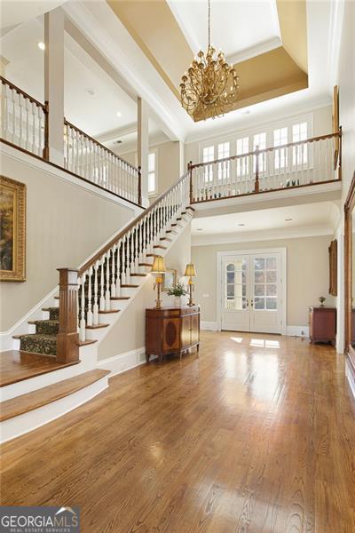 unfurnished living room featuring hardwood / wood-style flooring, a raised ceiling, and a towering ceiling