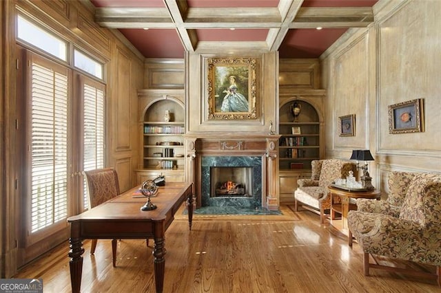 sitting room featuring wood walls, beam ceiling, a premium fireplace, coffered ceiling, and built in features