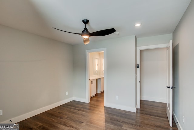 unfurnished bedroom with ceiling fan, dark wood-type flooring, connected bathroom, and a closet