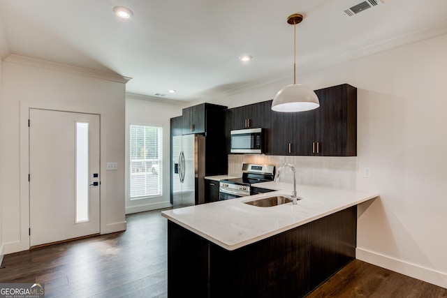 kitchen with appliances with stainless steel finishes, decorative light fixtures, sink, dark hardwood / wood-style floors, and kitchen peninsula