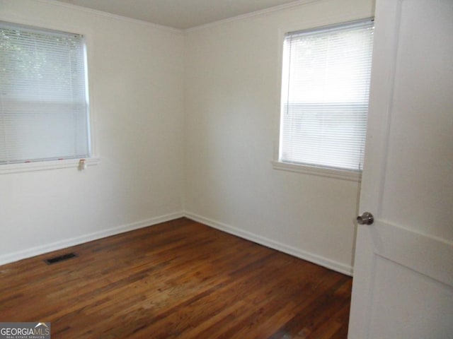 spare room featuring dark hardwood / wood-style flooring and crown molding