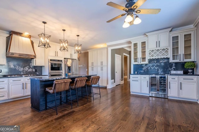 kitchen featuring stainless steel appliances, dark stone countertops, decorative backsplash, wine cooler, and a center island with sink