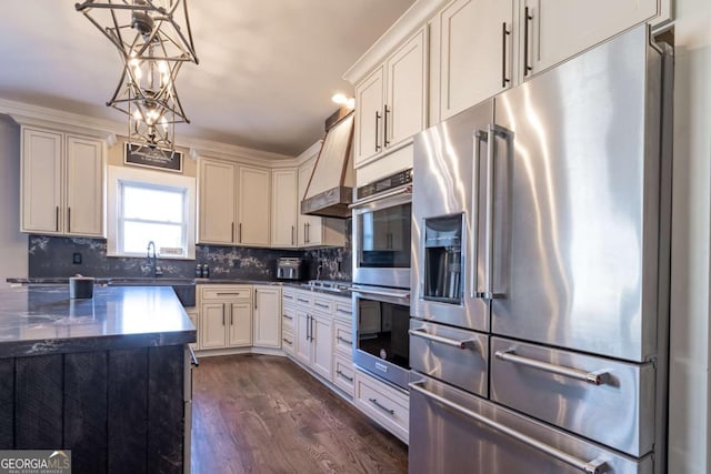 kitchen with white cabinets, appliances with stainless steel finishes, dark wood-type flooring, premium range hood, and hanging light fixtures