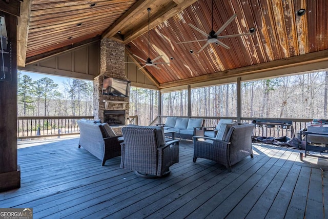 wooden terrace with ceiling fan and an outdoor living space with a fireplace